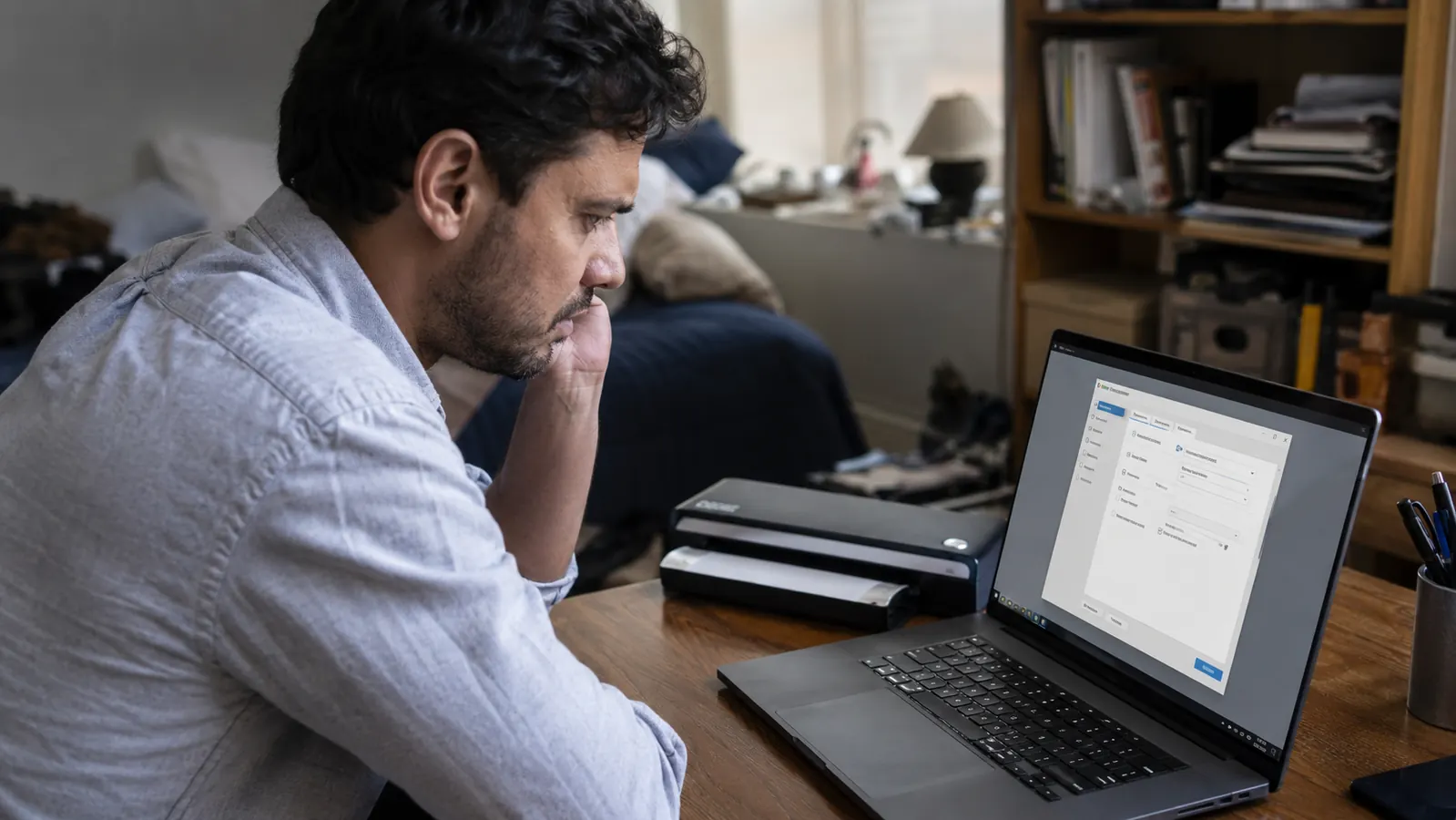 Remote worker troubleshooting scanner driver software on a laptop at a home office desk